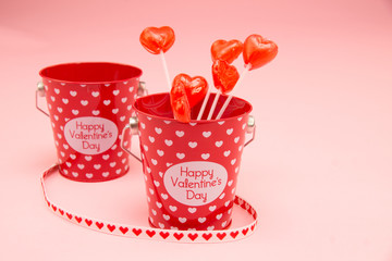 Valentine's day bucket with hearts and lollipops on pink 