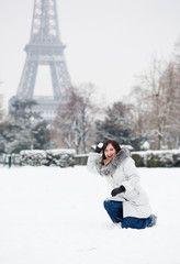 Fototapeta na wymiar Piękna dziewczyna gra śnieżkami w pobliżu wieży Eiffla w Paryżu