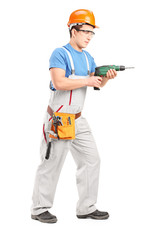 Full length portrait of a manual worker with helmet using a dril