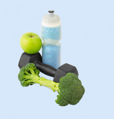 Dumbbells made of broccoli with water bottle and green apple