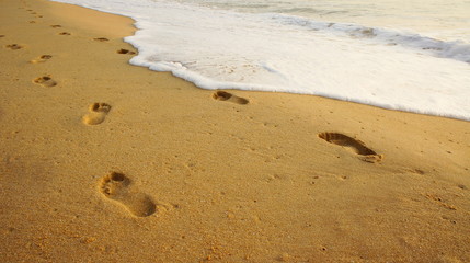 Footprints on yellow sand on the beach.