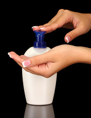 woman squeezing lotion on her hand, on black background