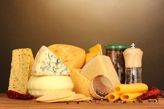 Various types of cheese on wooden table on brown background