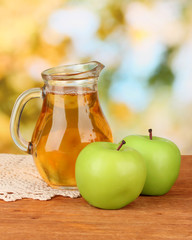 Full jug of apple juice and apple