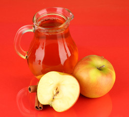 Full jug of apple juice and apple on color background