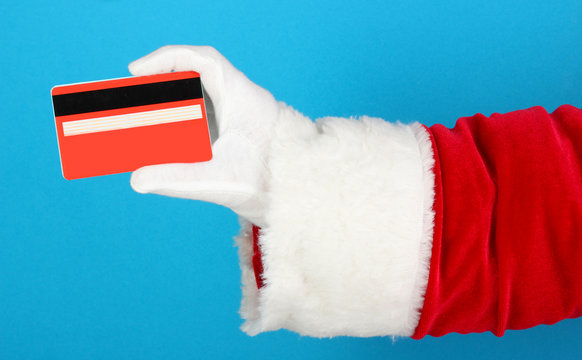 Santa Claus Hand Holding Red Credit Card On Blue Background