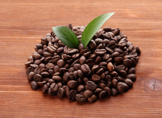 Coffee beans with leaves on wooden background