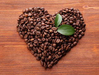 Coffee beans with leaves on wooden background