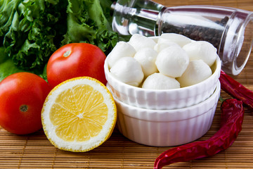 Mini mozzarella in ceramic cup with tomato, lettuce and lemon