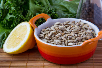 Peeled sunflower seeds in orange cup with lemon