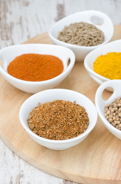 collection of spices in white bowls (coriander, cumin, paprika)