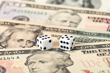 Two dice laying over a pile U.S. dollars