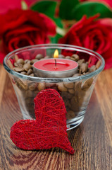 red candle in a glass cup with coffee beans and decorative heart