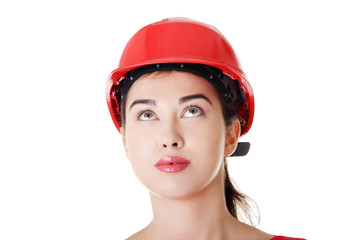 Confident female worker in helmet looking up.