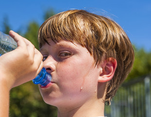 young boy drinks water out of a bottle