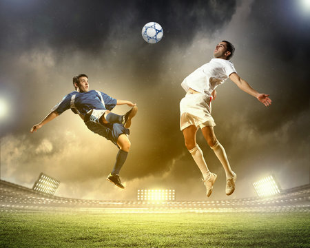 two football players striking the ball