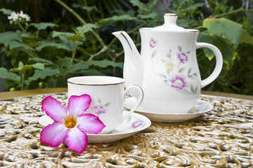 Tea Time in the Garden with Desert Rose Flower on Golden Table