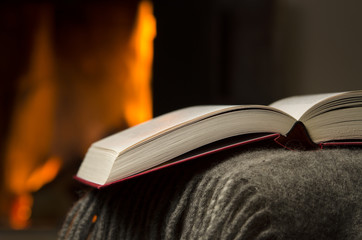 Peaceful and warm closeup of a open book by fireplace.