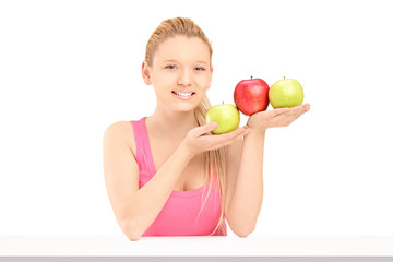 Young beautiful female sitting and holding apples