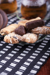 A plate with cookies next to two cups of tea
