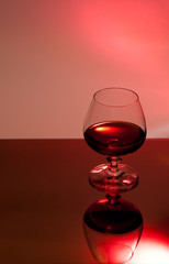 Ein Glas mit Alkohol vor rotem Hintergrund