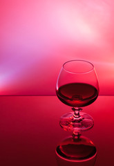 Ein Glas mit Alkohol vor rotem Hintergrund