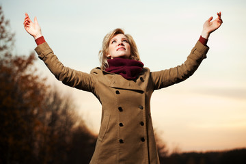 Woman with arms raised against a sky