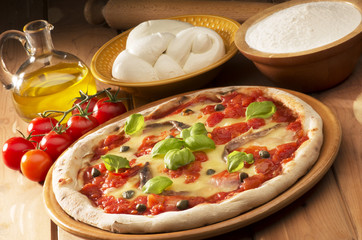 pizza with ingredients on wooden table