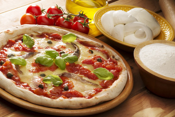 pizza with ingredients on wooden table