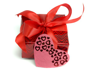 Red gift tied up by a bow and a card heart