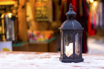 Burning christmas lantern on table with snow