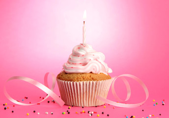 tasty birthday cupcake with candle, on pink background