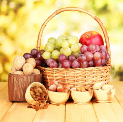 Grape in basket with nuts on wooden table