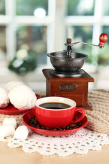 cup of coffee with scarf and coffee mill on table in room
