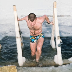 The man gets out of the ice on the Lake in winter