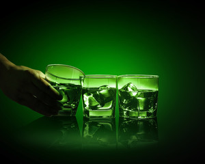 Three glasses of green absinth with ice cubes