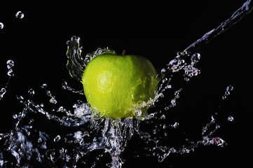 Fototapeta na wymiar Green apple water splash on black background