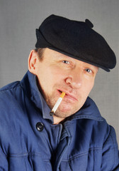 Marginal man in a cap with a cigarette