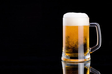 Mug fresh beer with cap of foam on a black background