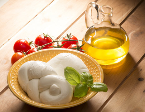 mozzarella cheese with olive oil and tomatoes on wooden table
