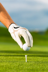 Hand hold golf ball with tee on course
