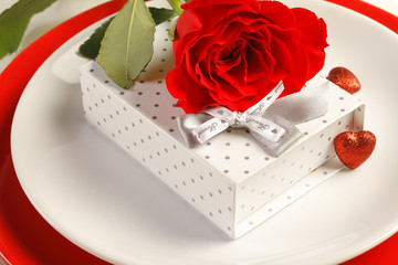 Romantic dinner setting with a rose and gift box