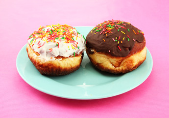 Tasty donuts on color plate on color background