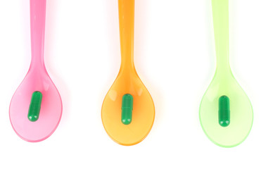 Plastic spoons with color pills, isolated on white
