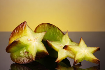 Fototapeta premium Two ripe carambolas on yellow background