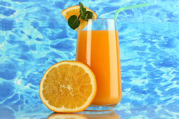 Glass of orange juice with mint and orange on sea background