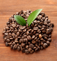 Coffee beans with leaves on wooden background