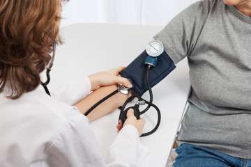 Doctor checking blood pressure with sphygmomanometer