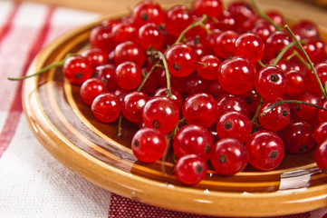 Berries of a red currant in a plate on a table