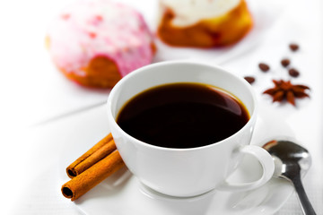 Cup of coffee and sweets on white background